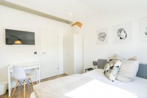 a white bedroom with a bed and a desk at T11-Appartements & Boardinghouse in Villingen-Schwenningen