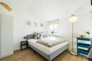 a white bedroom with a bed and a lamp at T11-Appartements & Boardinghouse in Villingen-Schwenningen