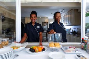 Forest Manor Boutique Guesthouse في ديربان: سيدتان واقفتان في مطبخ مع طعام