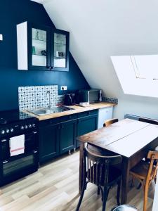 eine Küche mit blauen Schränken und einem Holztisch in der Unterkunft La Grange de l’ecuyer in Chemilly