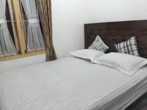 a bed with white sheets and pillows in a room at BUMiMi HOMESTAY in Painan