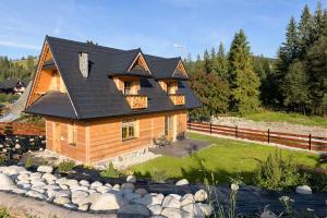 a log house with a black roof and a yard at Góralski Domek Sucha Woda in Małe Ciche