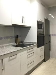 ミヤドイロにあるApartamento Luaのキッチン(白いキャビネット、黒い冷蔵庫付)