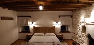 ein Schlafzimmer mit einem Bett und einer Steinmauer in der Unterkunft Braja House in Gjirokastër