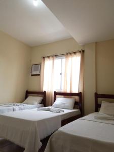 a room with three beds and a window at Pousada Brisa do Mar in Aracruz