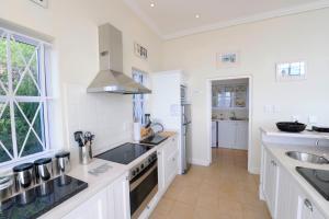 a kitchen with white cabinets and a sink at Felsensicht Holiday Home in Simonʼs Town
