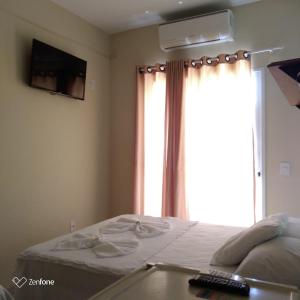 a bedroom with a bed and a window with a television at Pousada Brisa do Mar in Aracruz
