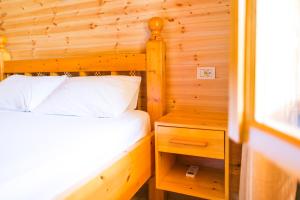 a bedroom with a bed and a wooden wall at Nashos Bungalows in (( Spile ))