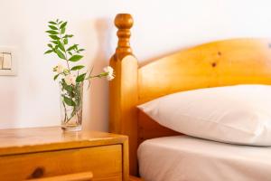 a vase with flowers on a table next to a bed at Nashos Bungalows in (( Spile ))