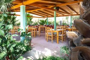 a restaurant with wooden tables and chairs under a roof at Nashos Bungalows in (( Spile ))