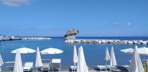 a group of white umbrellas and chairs on a beach at Hotel Villa Angelica in Ischia
