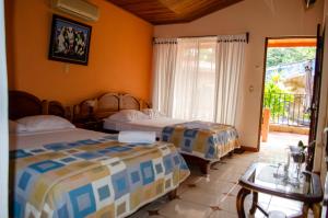 a bedroom with two beds and a window at Hotel y Restaurante Las Tablitas in Alajuela
