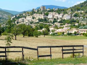 a fence in a field with a town on a hill at Studio Walla Confort Centre in Montbrun-les-Bains