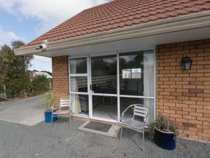 two chairs sitting in front of a house at Castle Court Motel in Wellsford