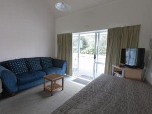 a living room with a blue couch and a tv at Castle Court Motel in Wellsford
