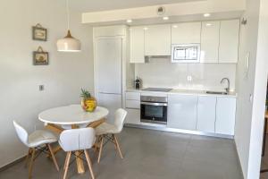エル・メダノにあるTEJITA BEACH APARTMENTの白いキャビネット、テーブルと椅子付きのキッチンが備わります。
