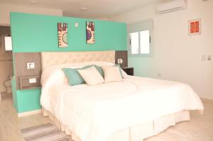 1 dormitorio con cama blanca y pared azul en ARROYO SUITE HOUSE en Mina Clavero