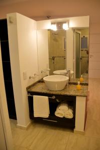 La salle de bains est pourvue d'un lavabo et d'un grand miroir. dans l'établissement ARROYO SUITE HOUSE, à Mina Clavero