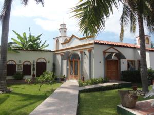 a church with a clock tower in a yard with palm trees at Hotel Hacienda Flamingos in San Blas