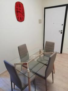 een glazen tafel met twee stoelen en een klok aan de muur bij Casa Tintilia in Isernia