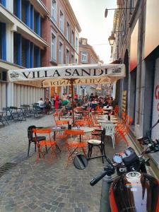 Bel appartement au cœur de Liège في لييج: مطعم بالطاولات والكراسي والناس جالسين على الطاولات