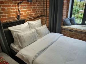 a bed in a room with pillows and a brick wall at БЕСКОНТАКТНОЕ ЗАСЕЛЕНИЕ - GoldenRingApartments - Flour Mill Loft in Yaroslavl