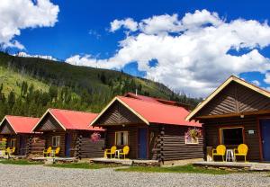 une cabane en rondins avec des chaises jaunes devant elle dans l'établissement High Country Motel and Cabins, à Cooke City