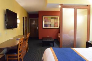 a hotel room with a bed and a desk and a table at Inn at the Finger Lakes in Auburn