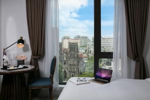 una habitación de hotel con un ordenador portátil en una cama y una ventana en The Oriental Jade Hotel en Hanói