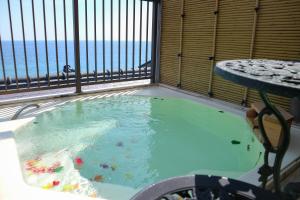 a hot tub on a balcony with a view of the ocean at HOTEL&RESORT Izu no Ne in Higashiizu