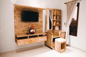 a room with a tv and a wooden wall at HOKYY Accommodation in Ubud