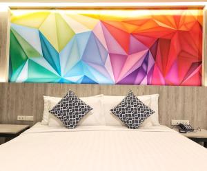 曼谷的住宿－叻差達迷你R酒店，色彩缤纷的墙壁前的一张带枕头的床