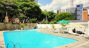 uma grande piscina azul com cadeiras e um guarda-sol em Royal Ibirapuera Park - Flat em São Paulo