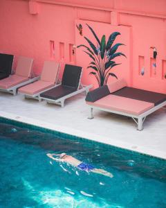 una piscina con tre sedie a sdraio accanto a un edificio di Sandalay Resort a Centro di Pattaya