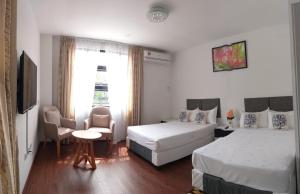 a hotel room with two beds and a chair at Coconut Bay Lodge in Bandar Seri Begawan