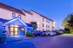 rząd samochodów zaparkowanych na parkingu obok budynku w obiekcie Comfort Hotel Linas - Montlhery w mieście Montlhéry