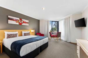 a hotel room with a large bed and a table at Quality Inn & Suites Traralgon in Traralgon
