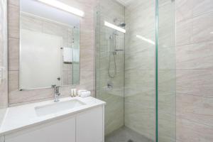 a bathroom with a sink and a glass shower at Knox International Hotel and Apartments in Wantirna