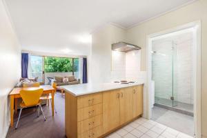 a kitchen and dining room with a glass shower at Knox International Hotel and Apartments in Wantirna