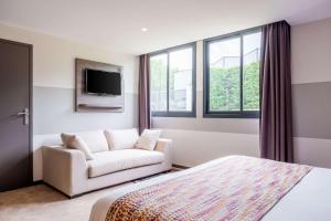 a bedroom with a bed and a couch and a tv at Best Western Portes d’Aquitaine Agen Sud in Le Passage