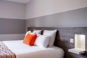 a bedroom with a bed with white and orange pillows at Best Western Portes d’Aquitaine Agen Sud in Le Passage