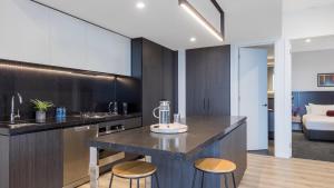 a kitchen with a counter and stools in a room at Avani Melbourne Box Hill Residences in Box Hill