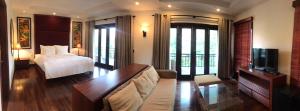 une chambre d'hôtel avec un lit, un canapé et une télévision dans l'établissement Luxury Purama Villas Da Nang- Free Pick up Airport, à Đà Nẵng