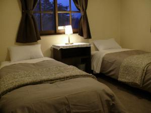2 camas en una habitación con ventana y lámpara en Country Inn Mori no Gorilla en Kitashiobara