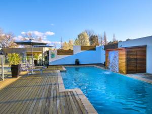 a swimming pool with a deck and a house at Myrtleford Motel on Alpine in Myrtleford