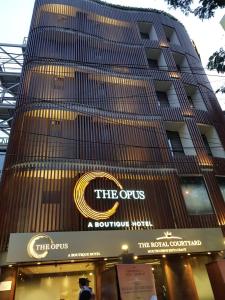 um edifício alto com um sinal em frente em The Opus Kolkata - A Boutique Hotel em Calcutá