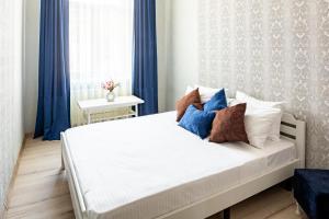 - une chambre avec un grand lit blanc et des rideaux bleus dans l'établissement Alfa Apartments Kniazia Romana 11, à Lviv