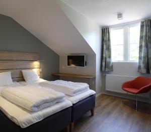 1 dormitorio con 2 camas y silla roja en Kvibergs Vandrarhem - Hostel, en Gotemburgo