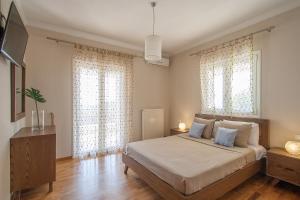 a bedroom with a large bed and two windows at Villa Sunny in Skiathos