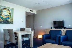 um quarto com uma mesa e cadeiras e uma televisão em Strandhotel Buren aan Zee em Buren